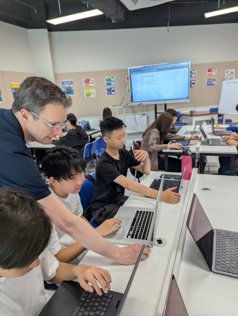 Simon Guest сурагчдад тусалж буй нь